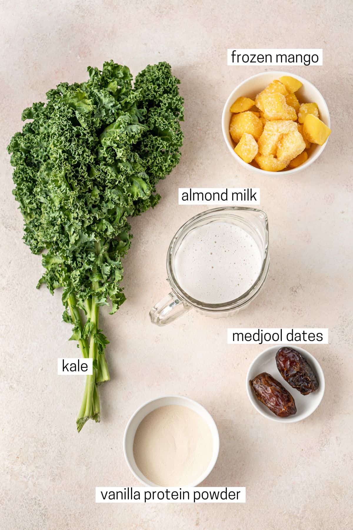 All ingredients needed to make a mango kale smoothie laid out in bowls.