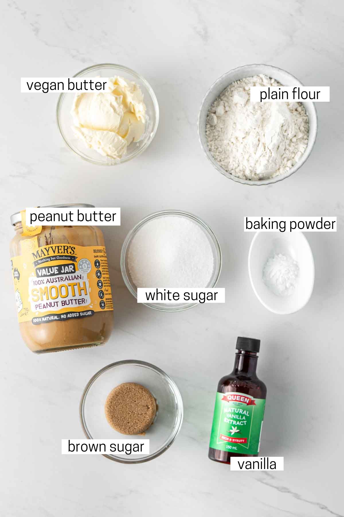 All ingredients needed to make peanut butter cookies laid out in bowls.