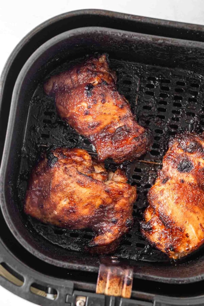 Cooked chicken thighs in the air fryer basket.