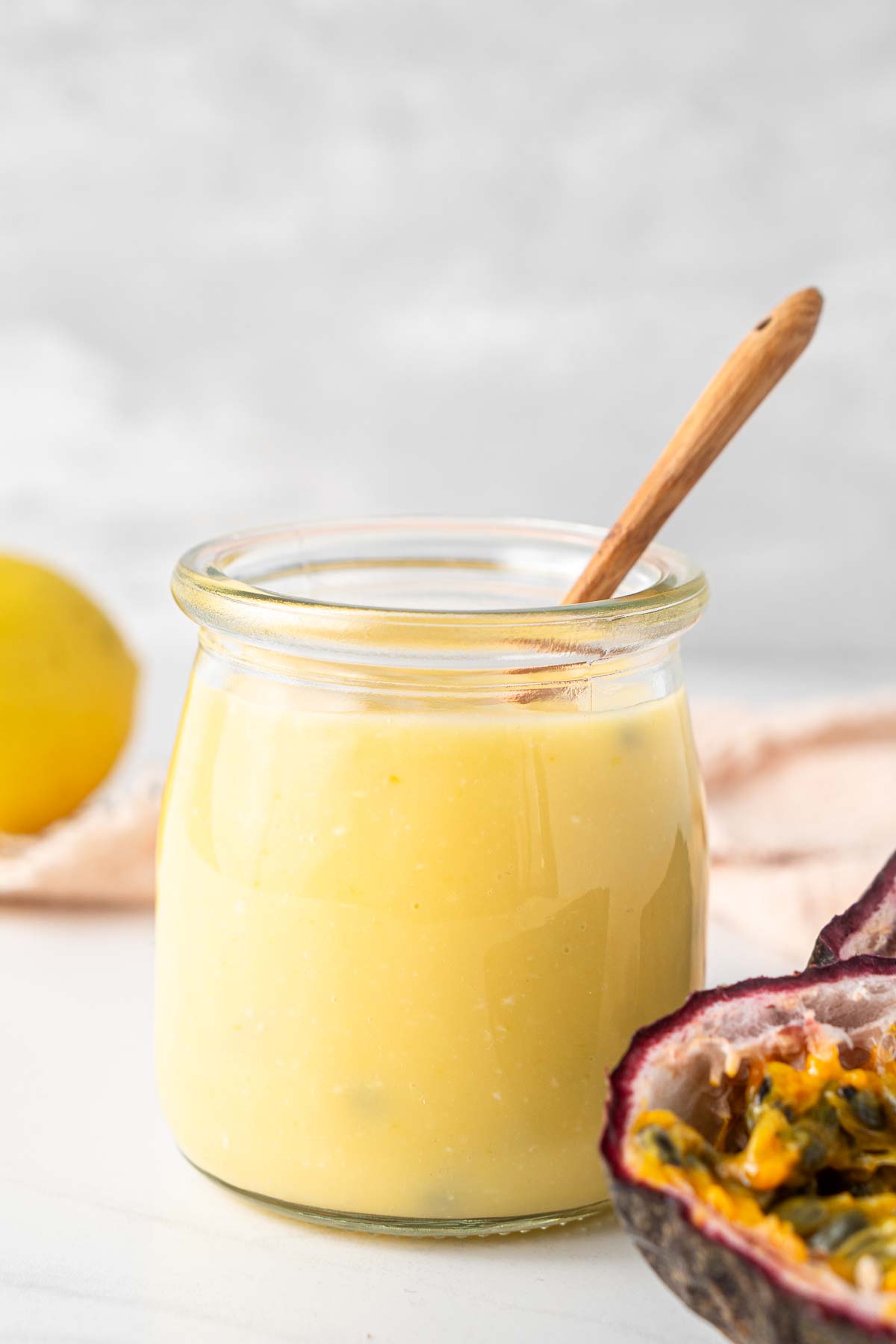 Dairy free passionfruit and lemon curd in a jar with a spoon.