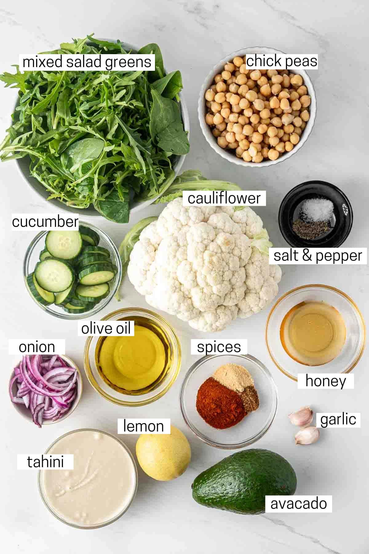 All ingredients needed to make cauliflower and chickpea salad with tahini dressing laid out in small bowls.