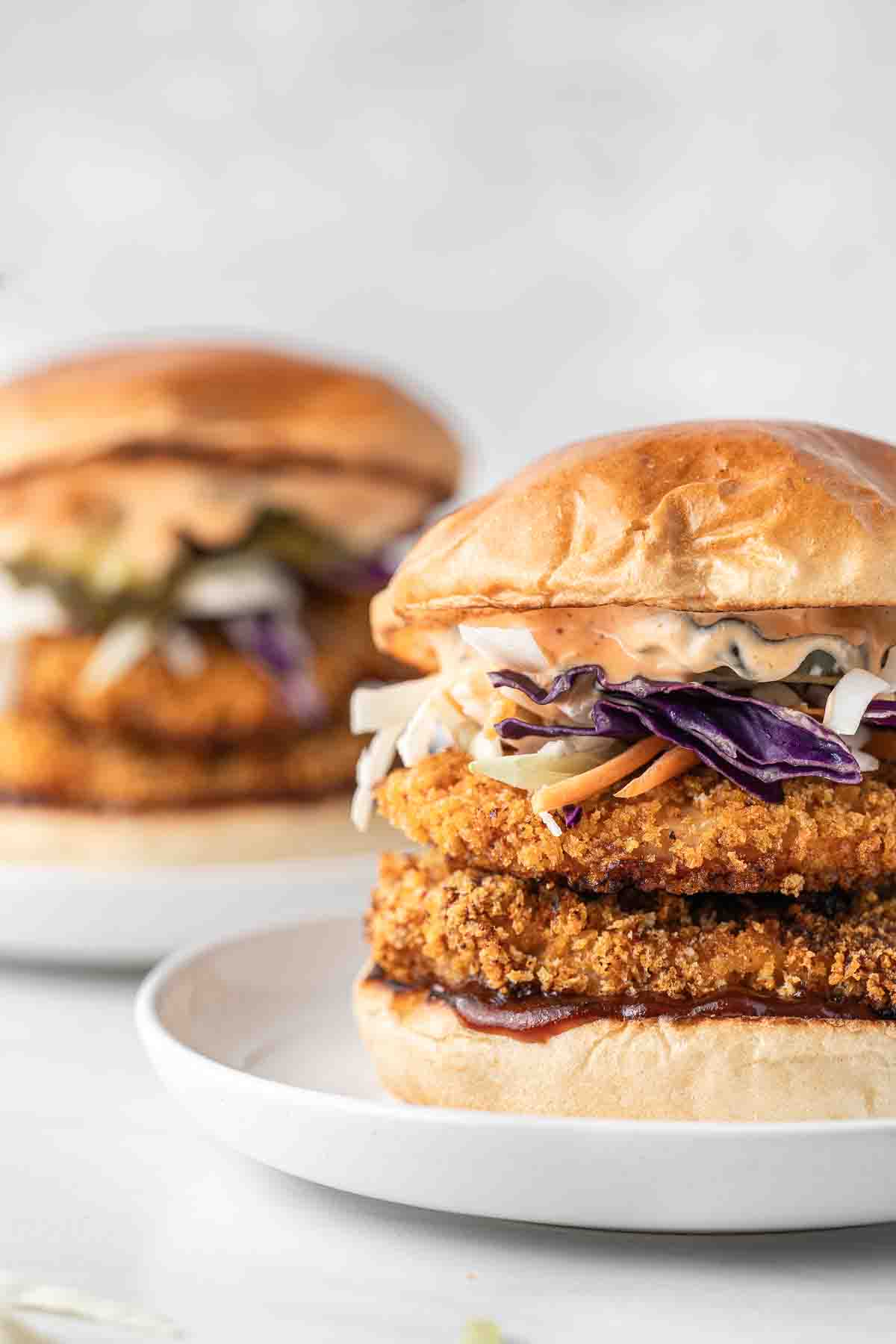 Close up of spicy chicken burger with 2 fillets, slaw and sauce.