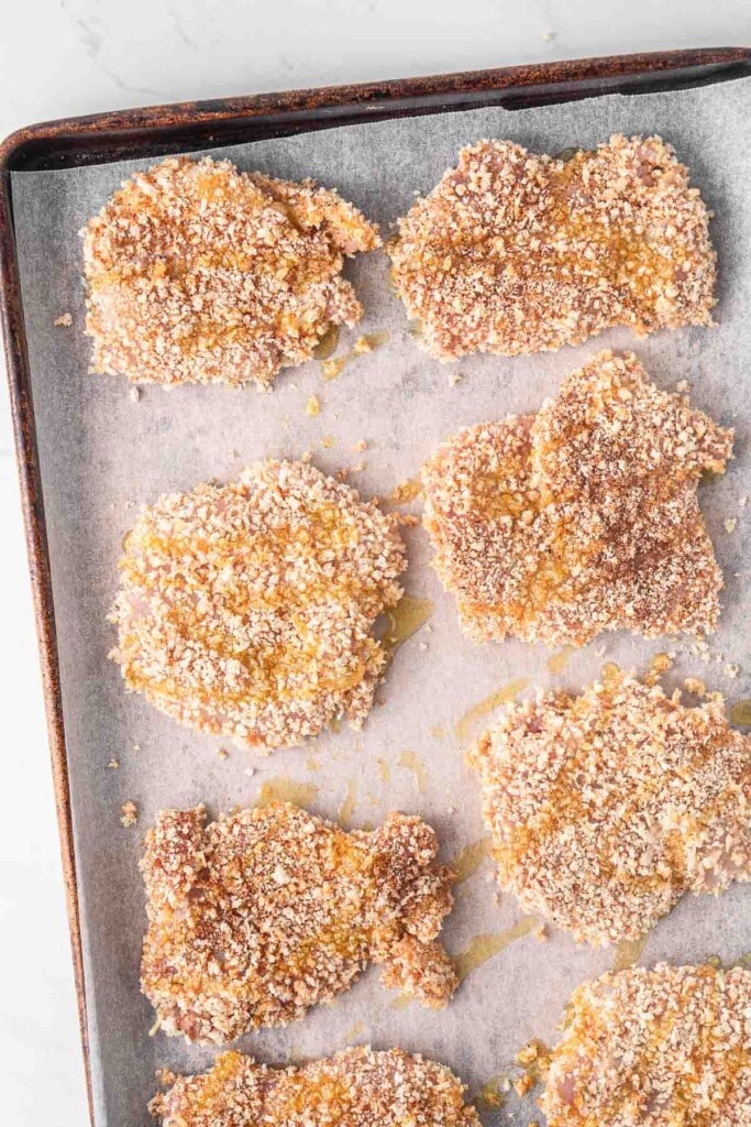 Crumbed chicken on a baking tray with olive oil.