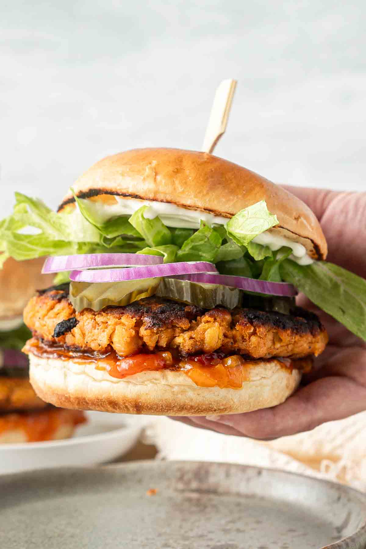 Sweet potato and chickpea burger being held up.