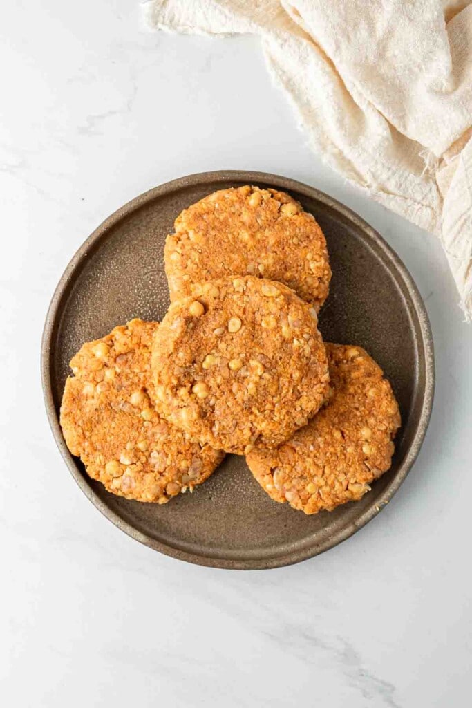 Sweet potato and chickpea burger patties shaped on a plate and ready to fry.
