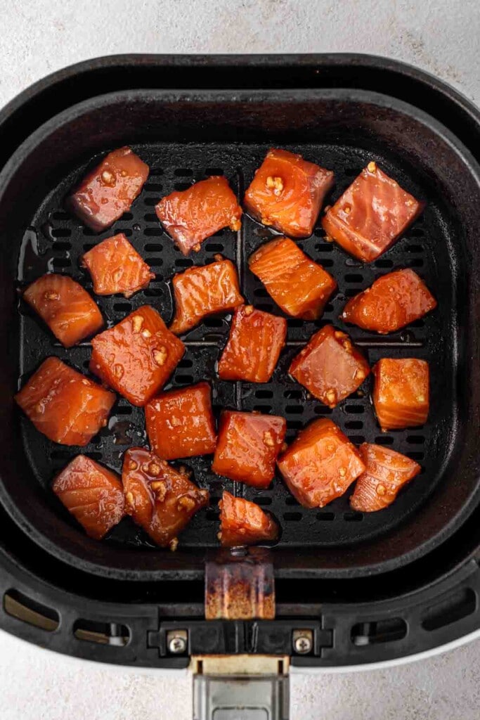 Raw marinated salmon in the air fryer basket. 