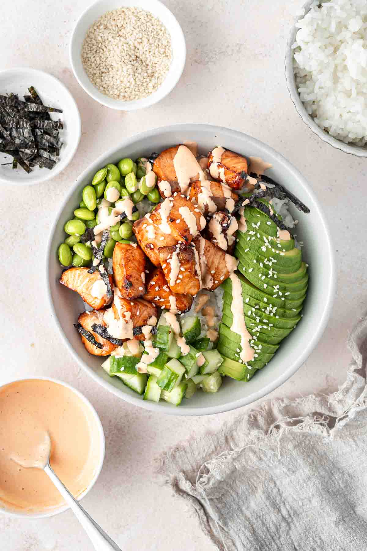 Air fryer salmon bowl with rice, edamame, cucumber, avocado and spicy mayo. 