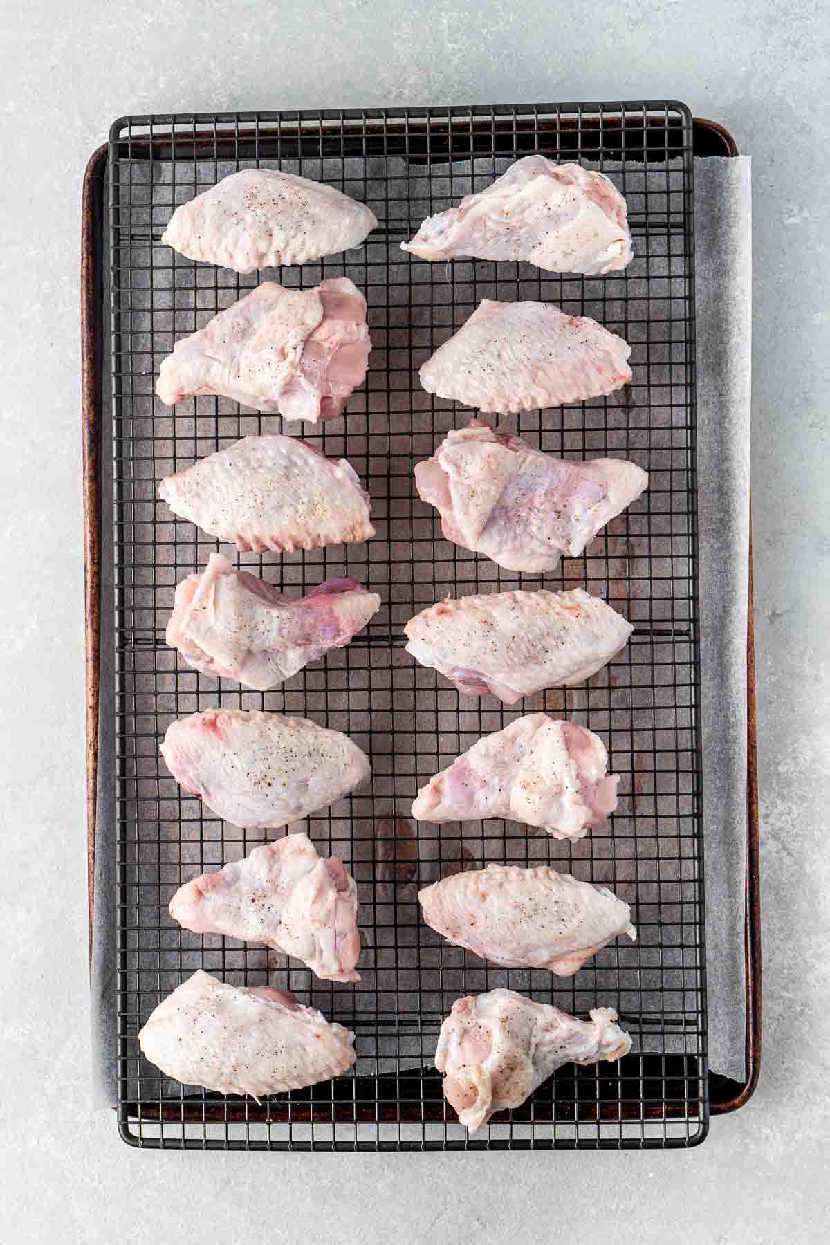Chicken wings cut and laid out on a wire rack over a baking tray.