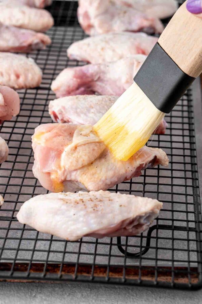 Brushing chicken wings with melted butter.