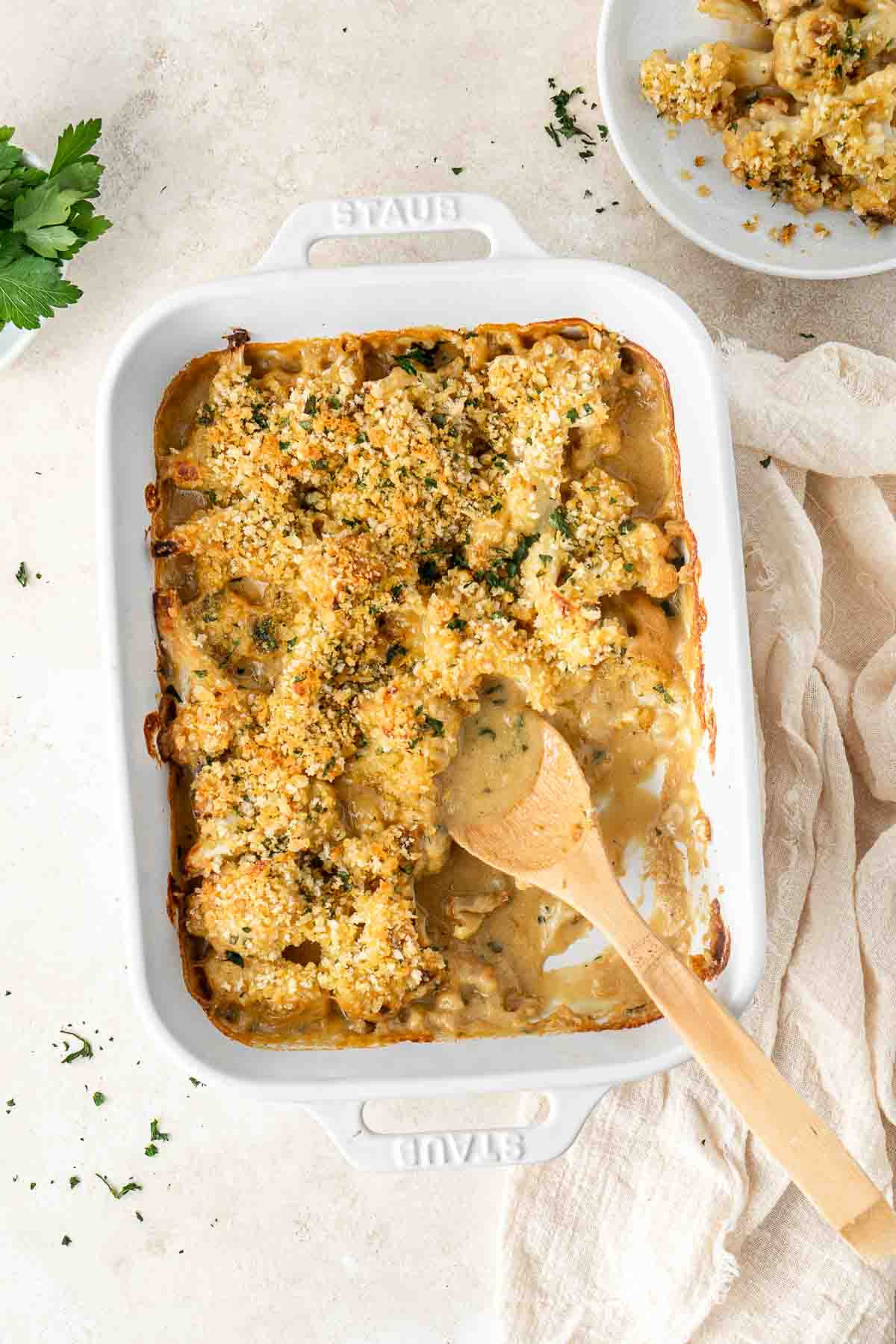 Vegan cauliflower cheese bake with a serving spoon.