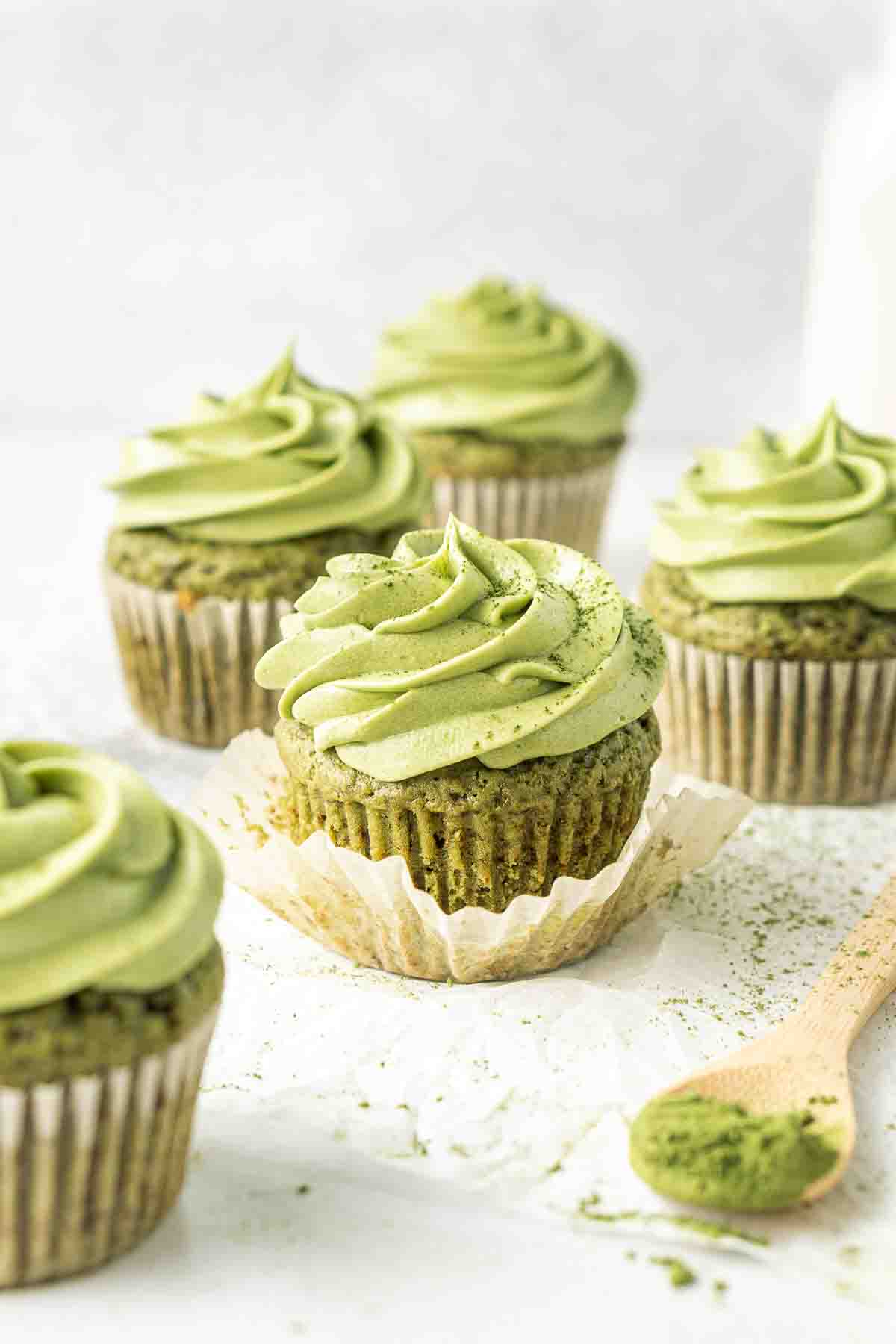 Close up of dairy free matcha cupcakes, one with the liner removed showing a green cake.