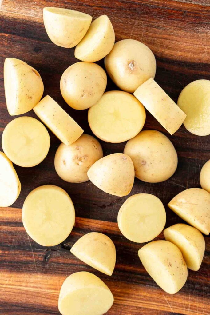 Cut baby potatoes on a chopping board.
