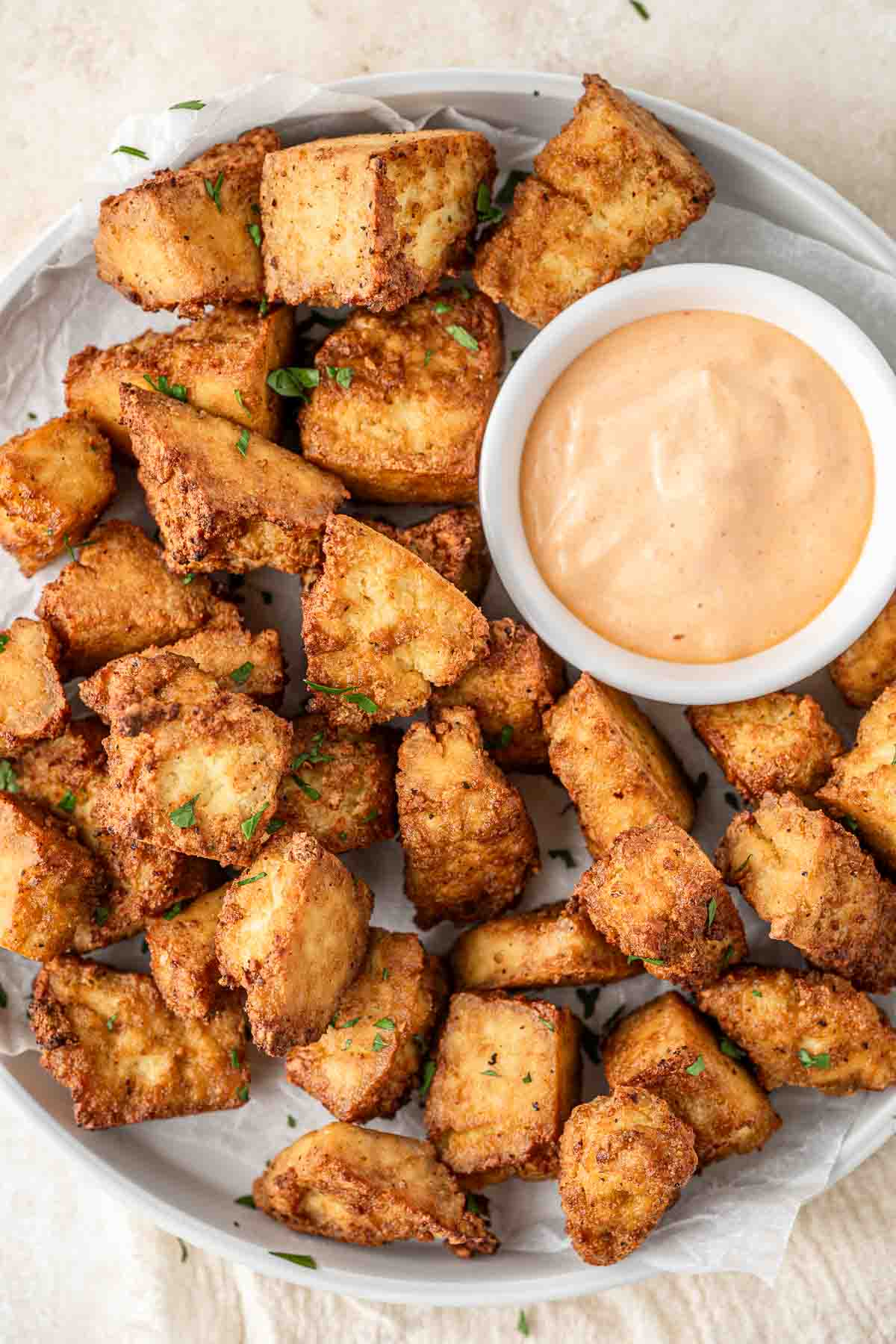 Crispy air fryer tofu nuggets on a plate with spicy mayo dipping sauce.