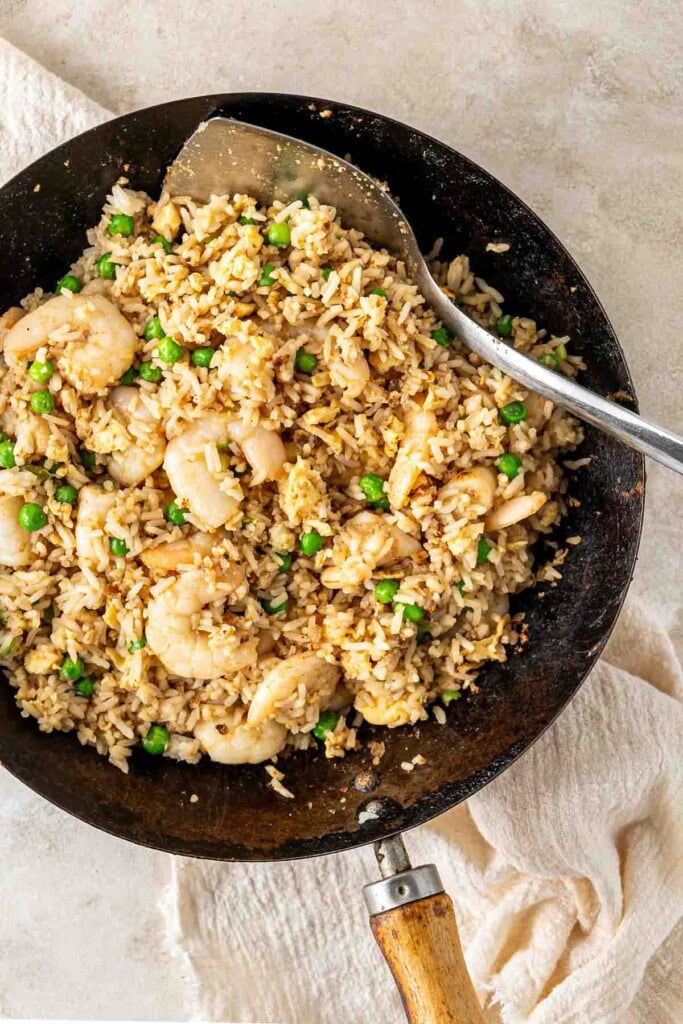 Prawn and egg fried rice with peas in a wok.