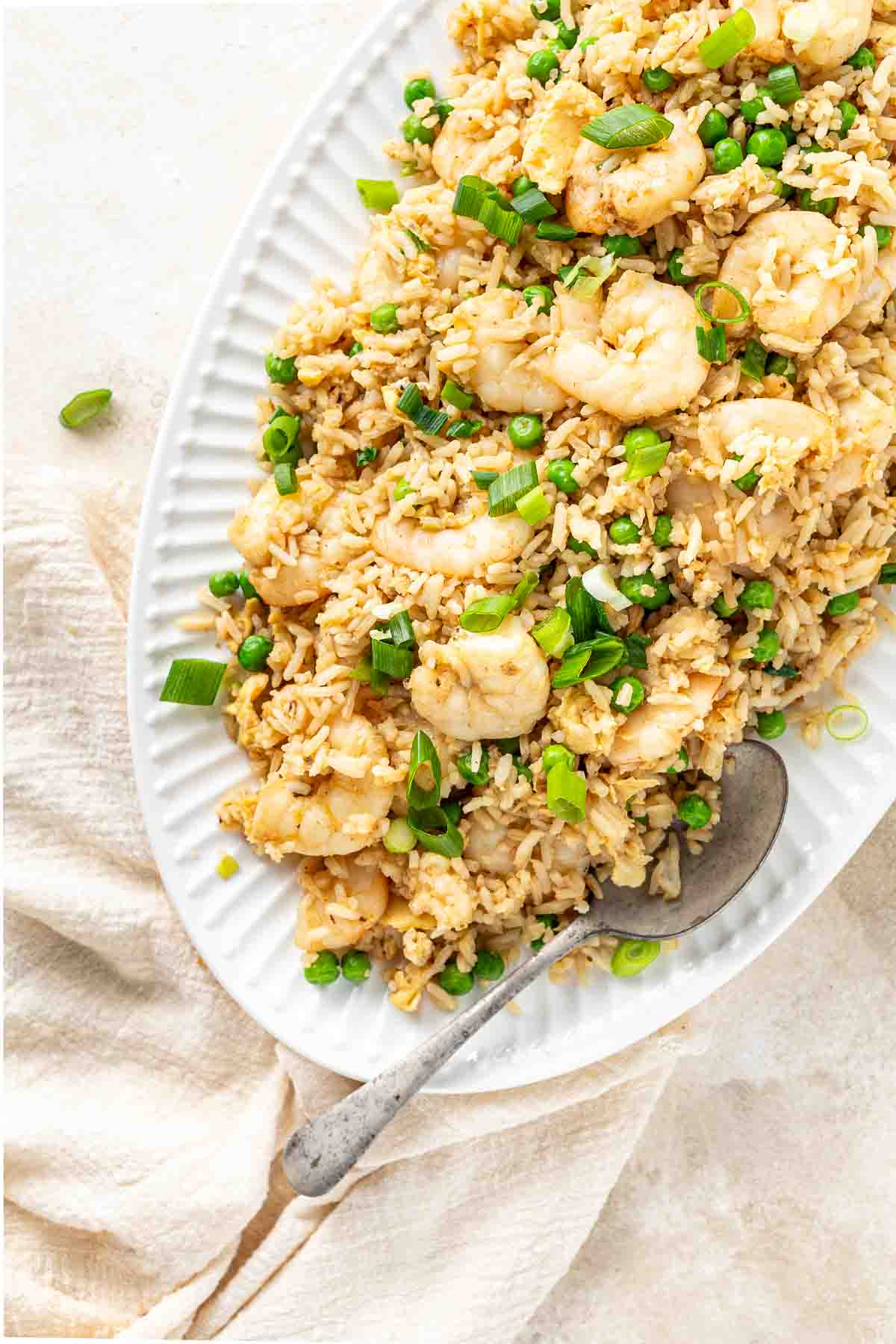 Prawn fried rice served onto a large plate with a spoon.