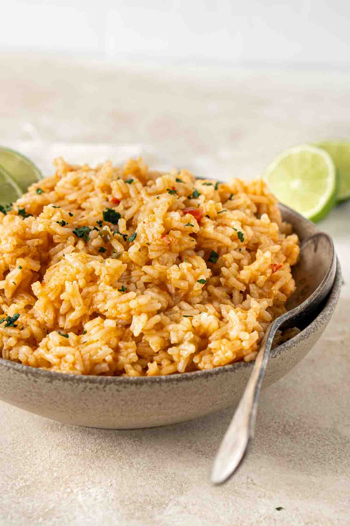 Mexican-style rice made in the rice cooker and served in a brown bowl with a spoon.