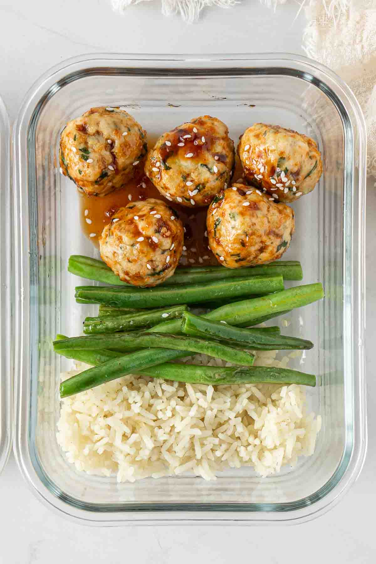 Close up of a meal prep container with the meatballs, beans and rice.