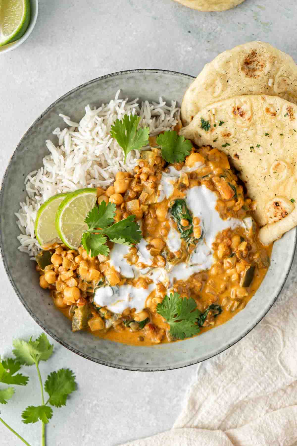 Chickpea and lentil curry served in a bowl with rice and naan.