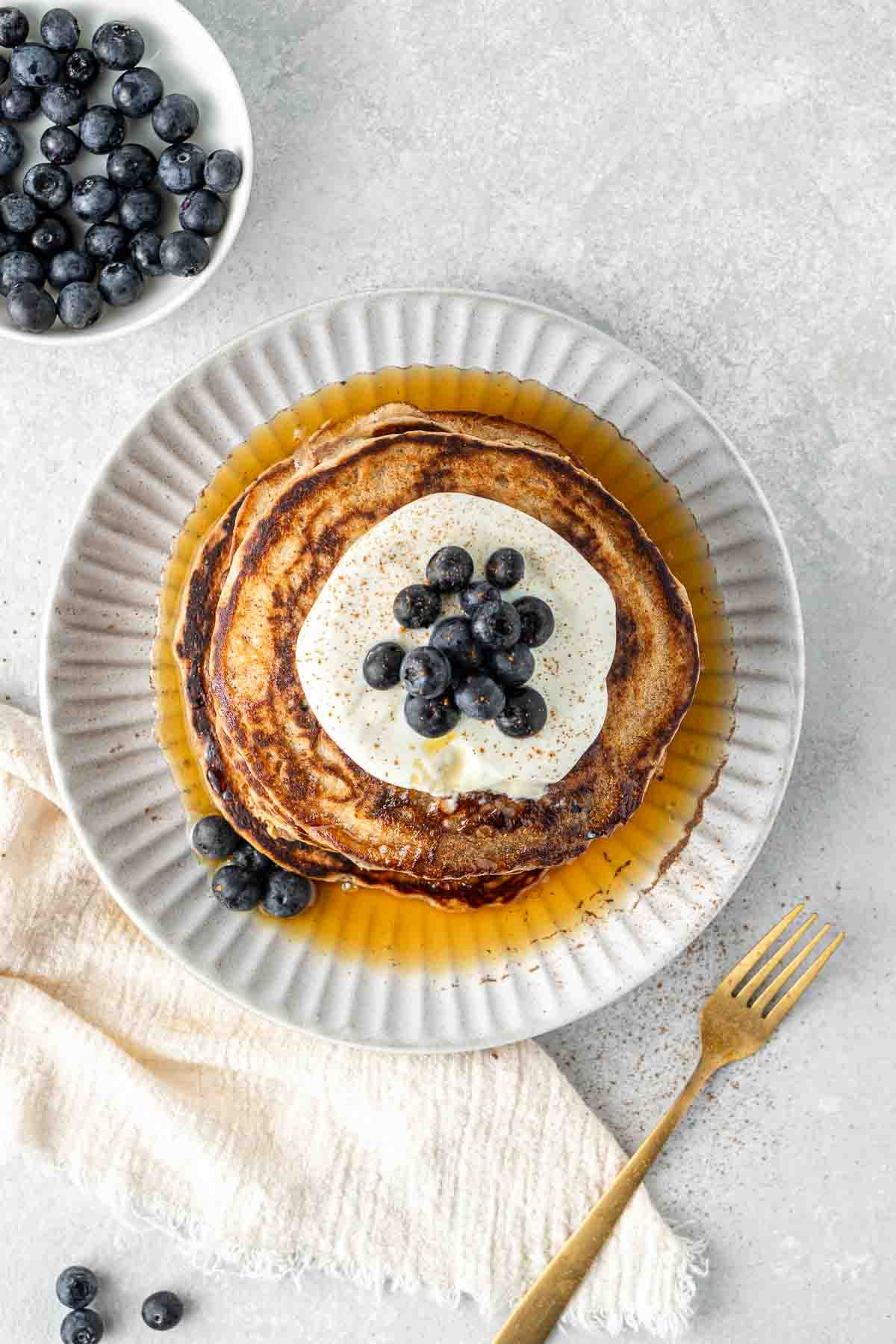 Overhead of blueberry pancakes topped with yoghurt and berries.