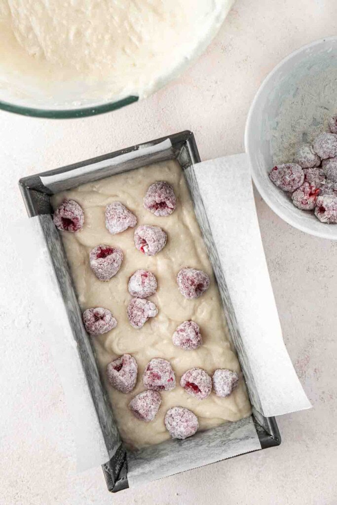 Dotting the flour covered berries into the cake pan.