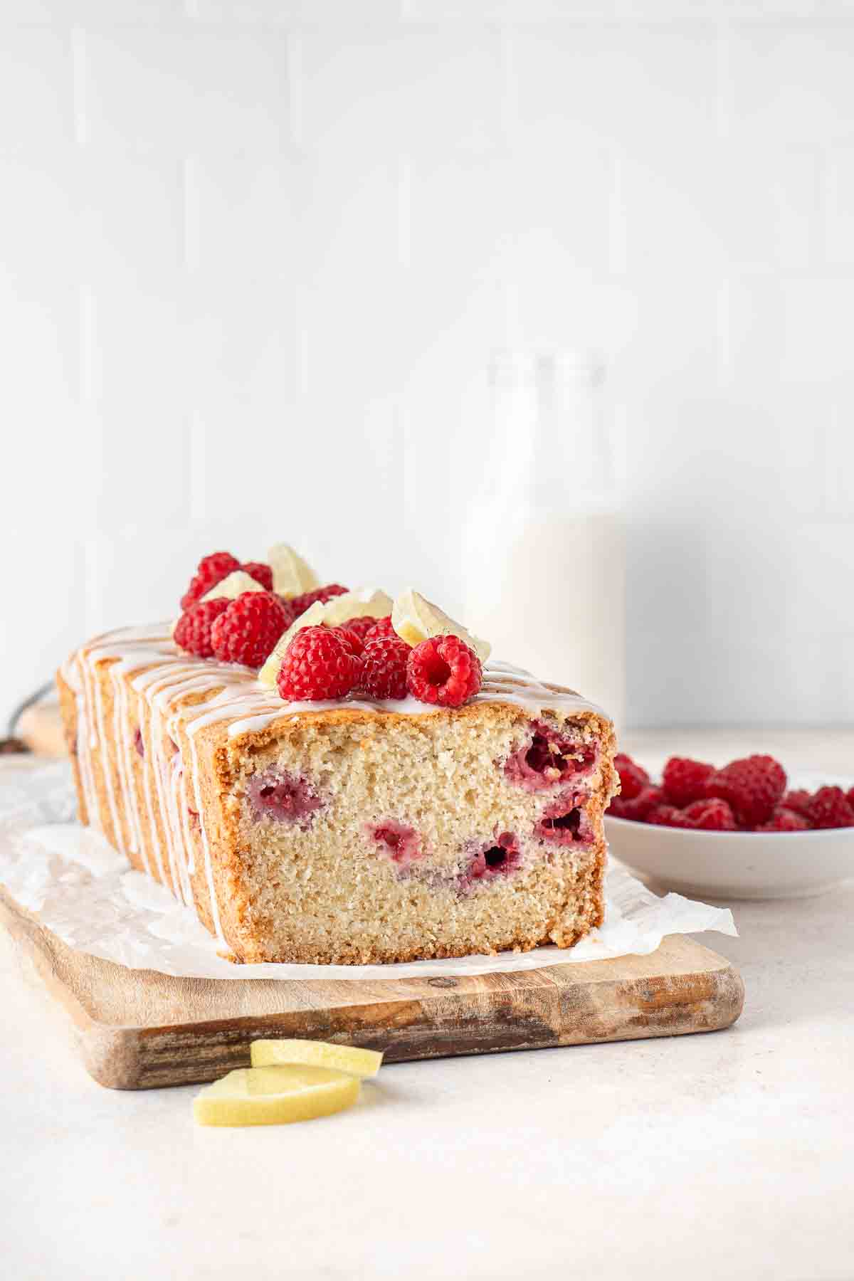 Raspberry and lemon loaf cake topped with more raspberries and lemon slices.