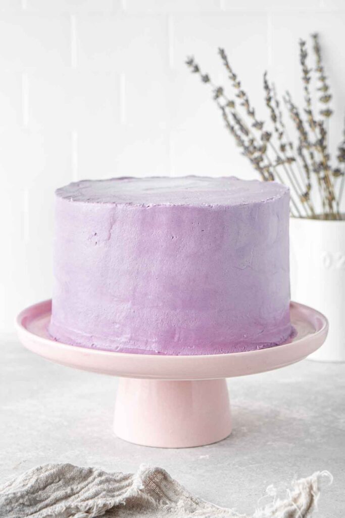 Purple frosted cake on a cake stand.