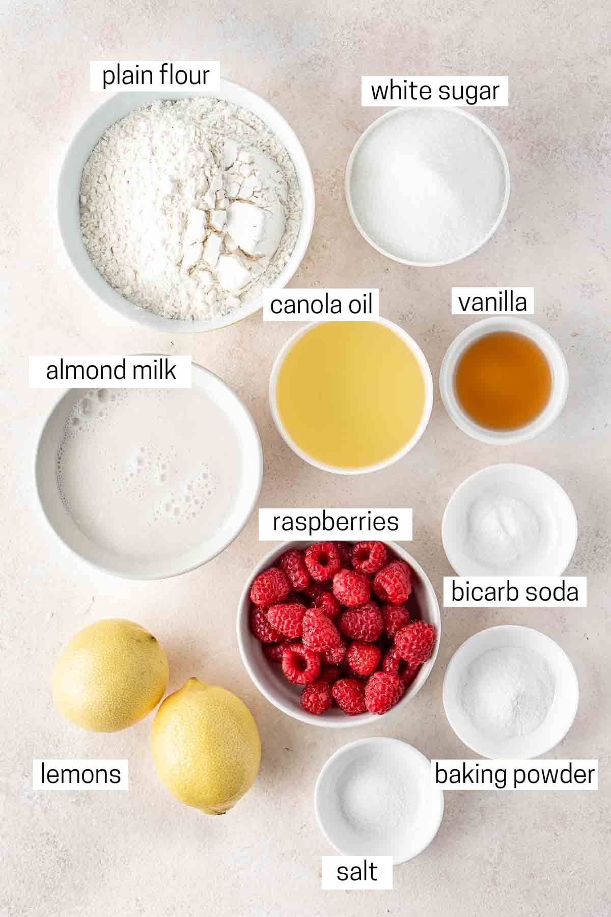 All ingredients needed to make raspberry and lemon loaf cake in small bowls.