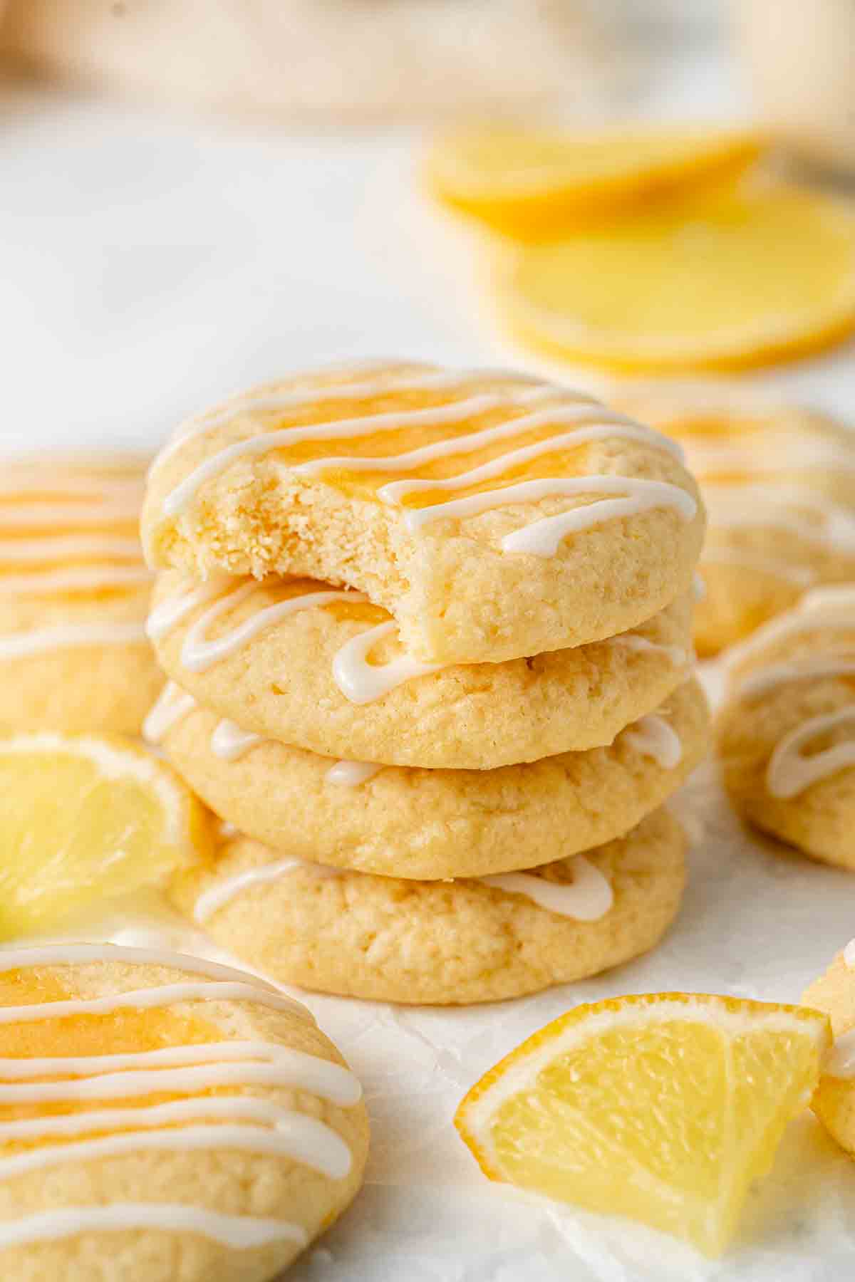 Stack of 4 lemon thumbprint cookies, one with a bite taken.
