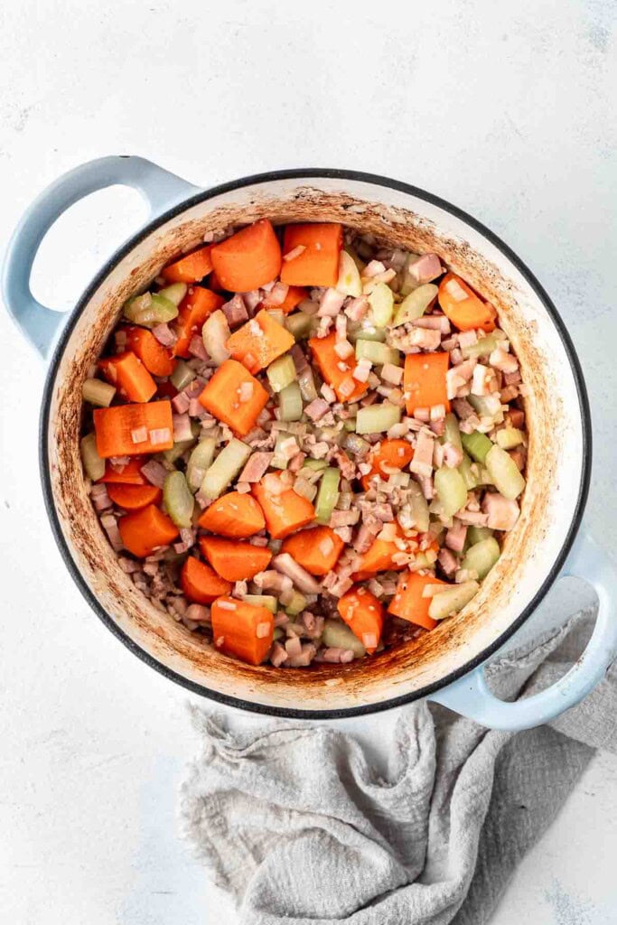 Sautéing vegetables and speck in a dutch oven.