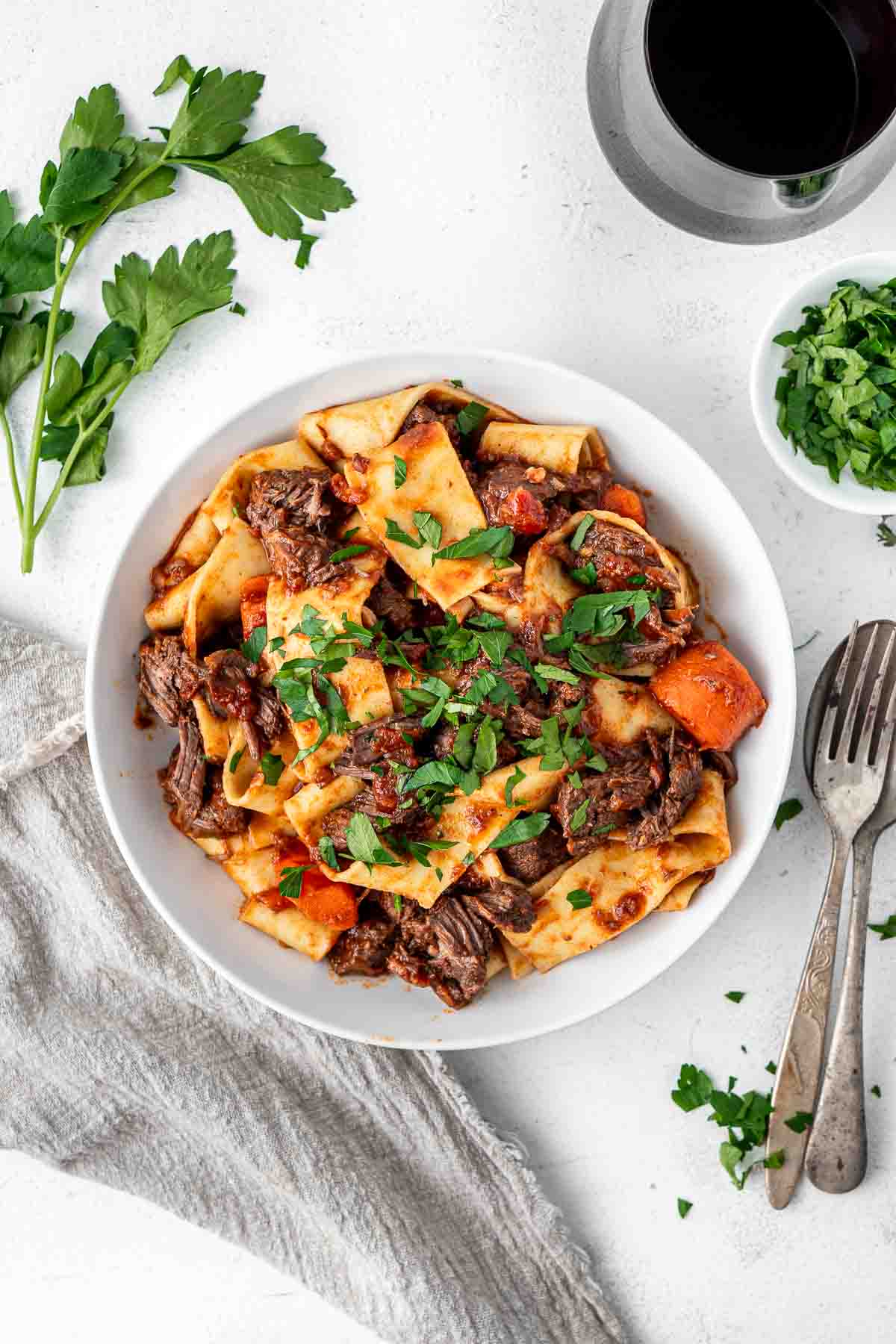 Beef ragu served in a white bowl with fresh parsley. 