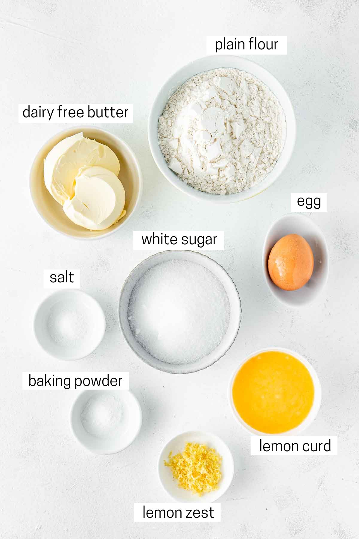 All ingredients needed to make lemon thumbprint cookies laid out in small bowls.