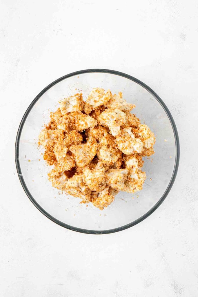 Crumbed pieces of cauliflower in a mixing bowl.