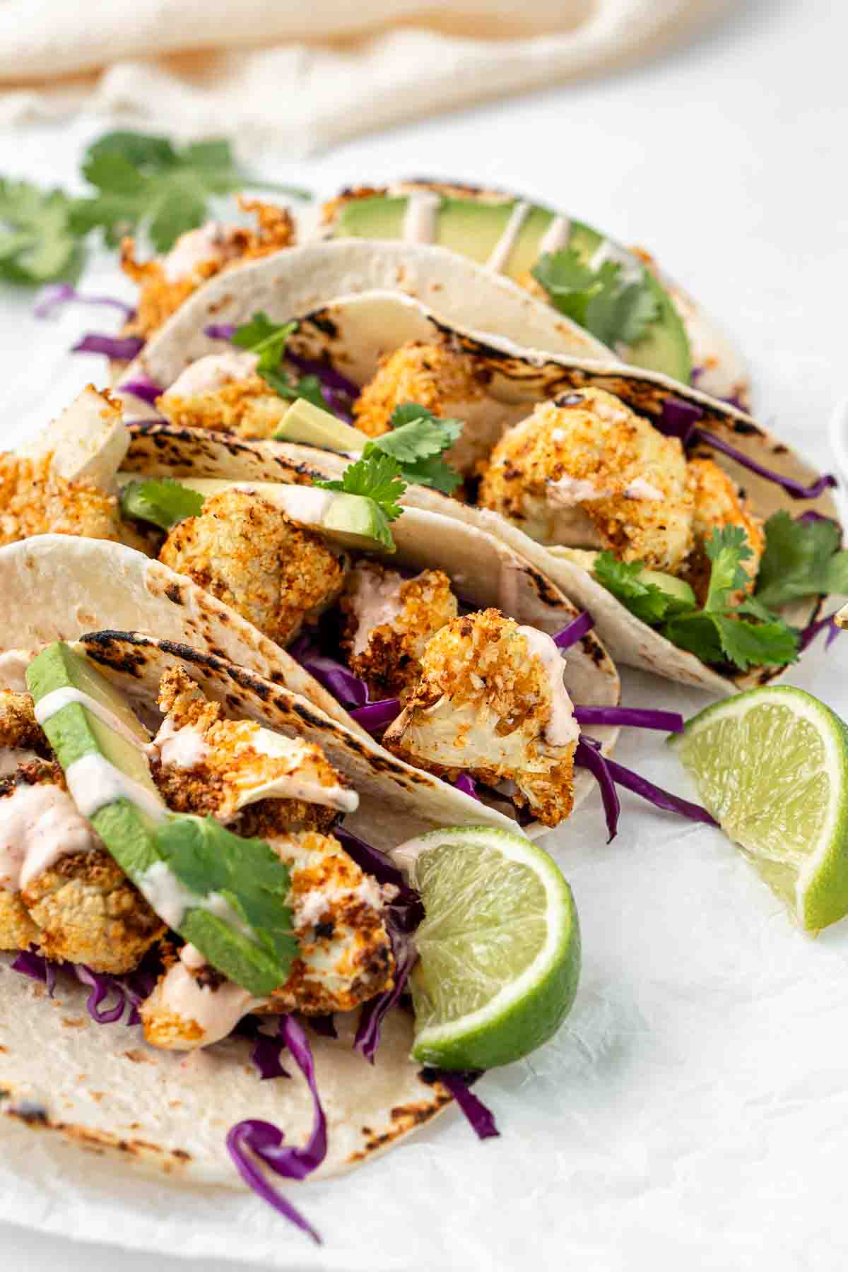 Close up of crispy air fryer cauliflower tacos with lime wedges.