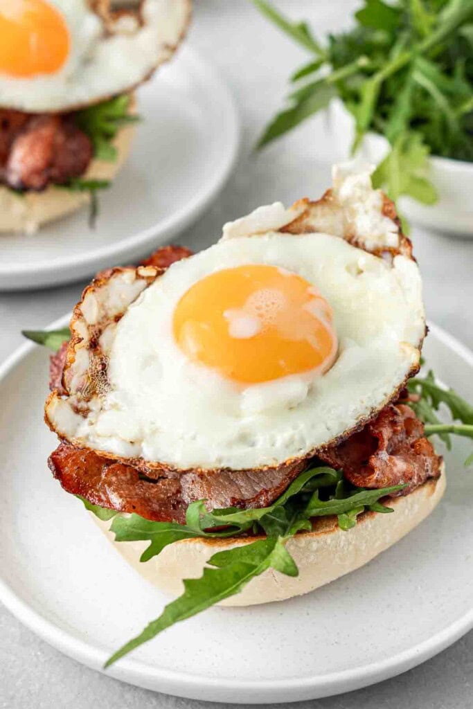 Assembling the rolls with an egg on top of the bacon.