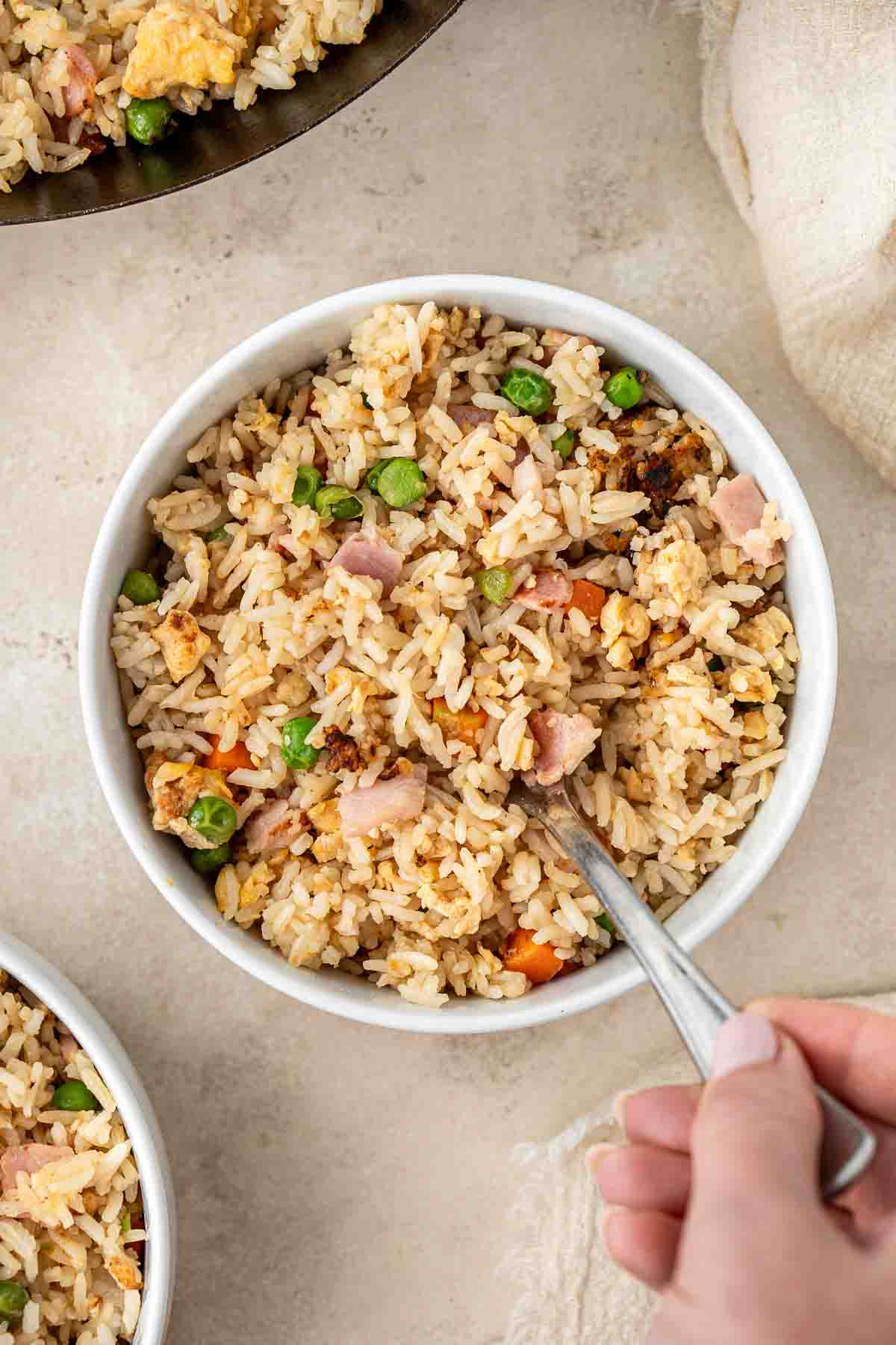 Bowl of fried rice with a fork taking a bite.