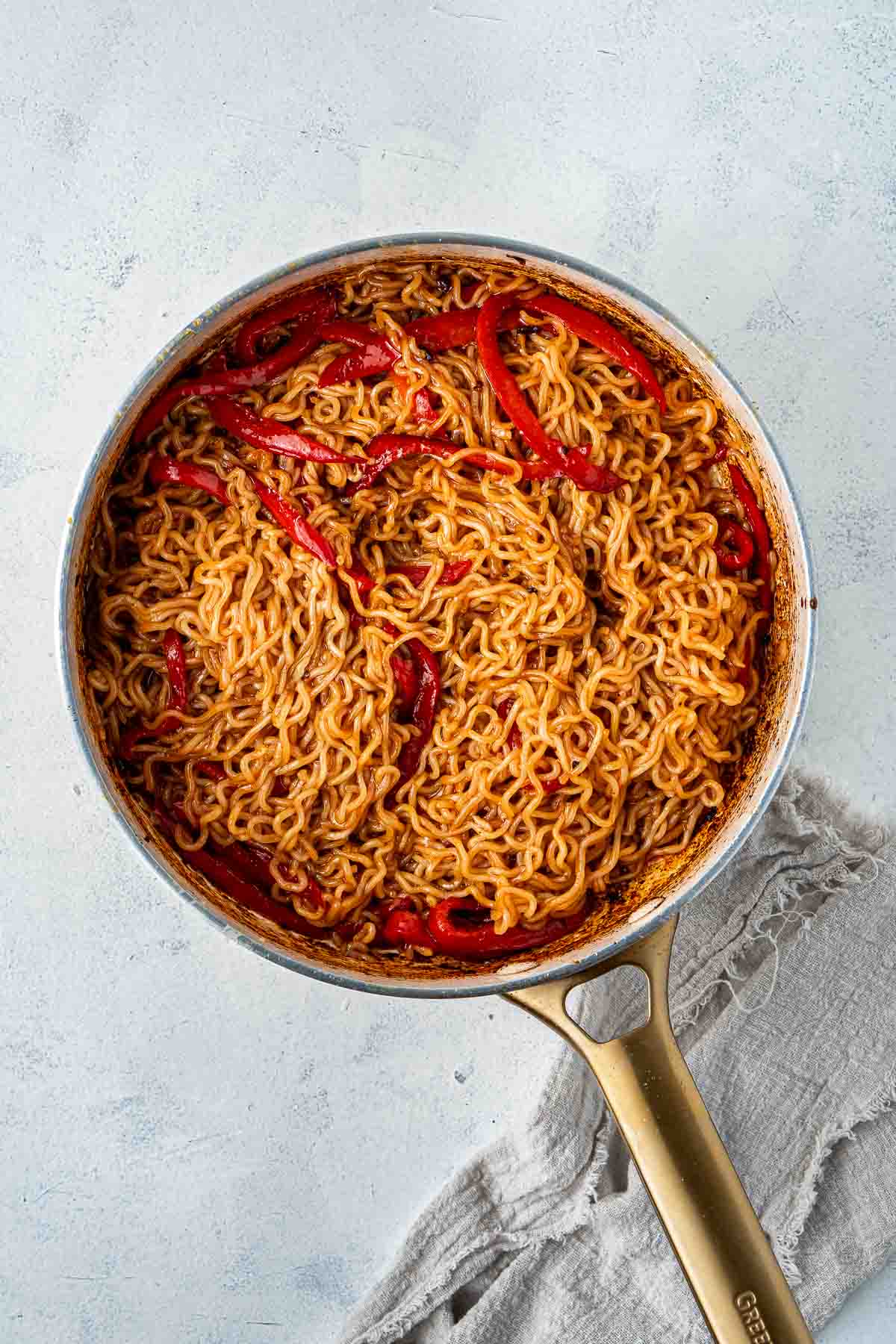 Spicy noodles and capsicum in a frying pan.