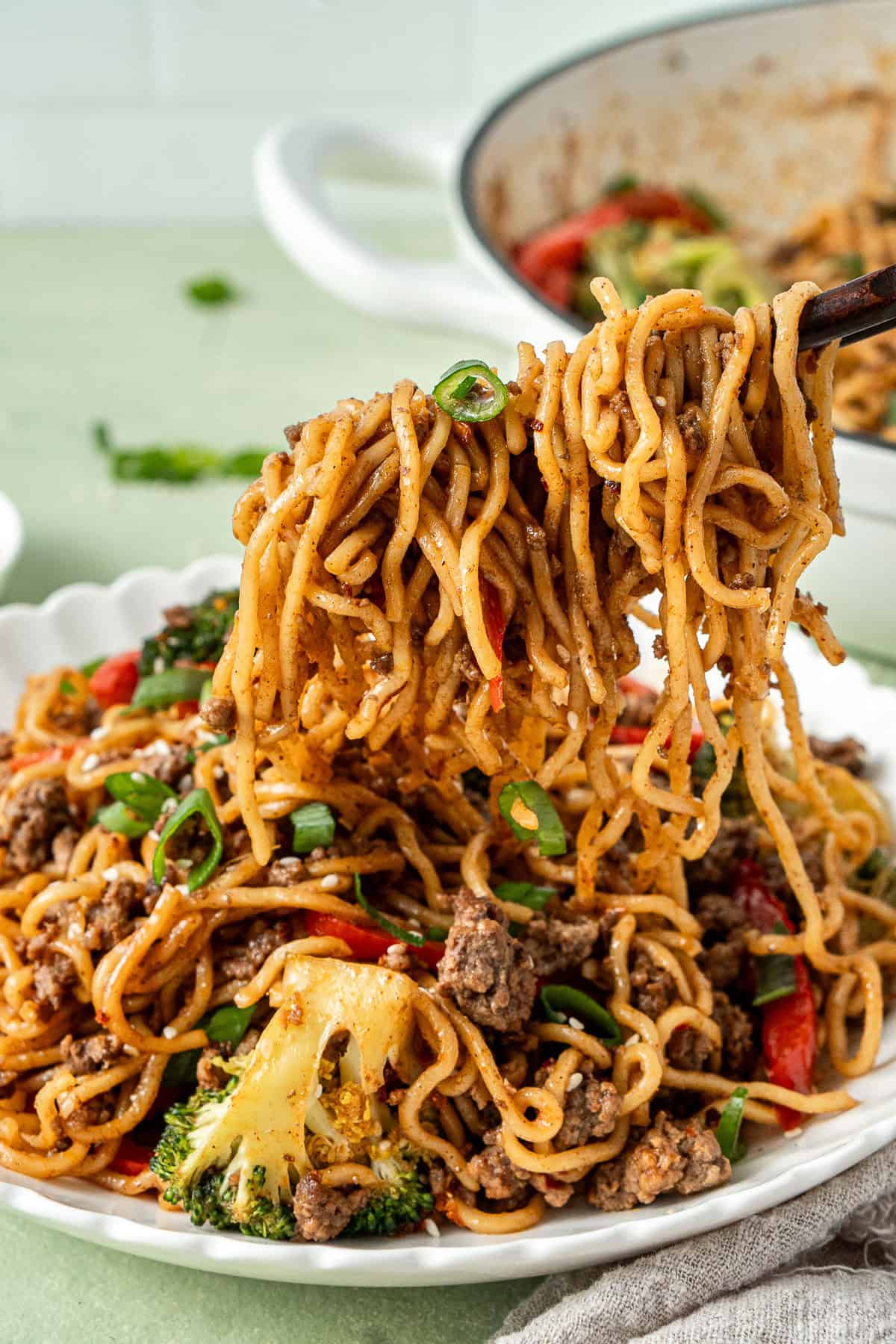 Chopsticks pulling the noodles from the bowl.