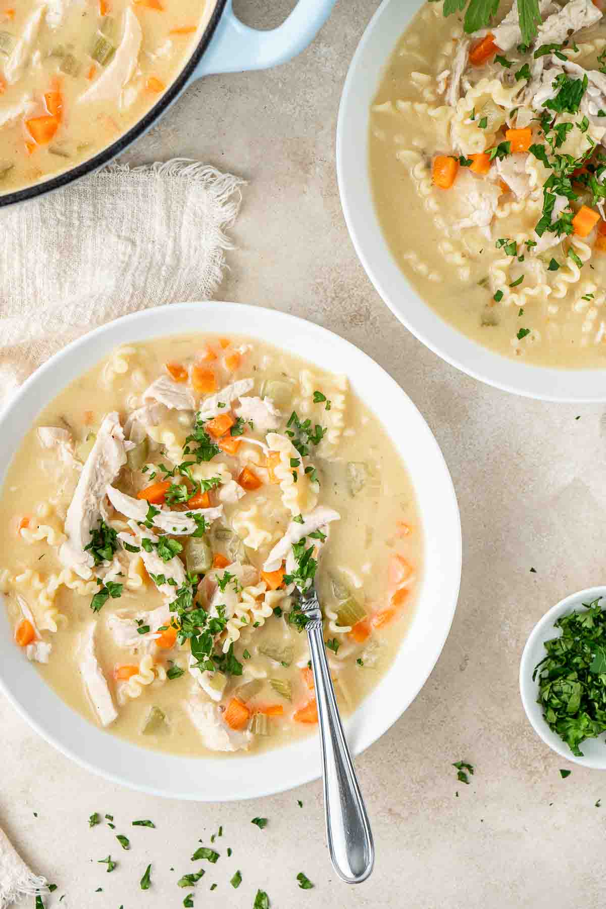 Creamy dairy-free chicken soup in a white bowl with a spoon and parsley on top.