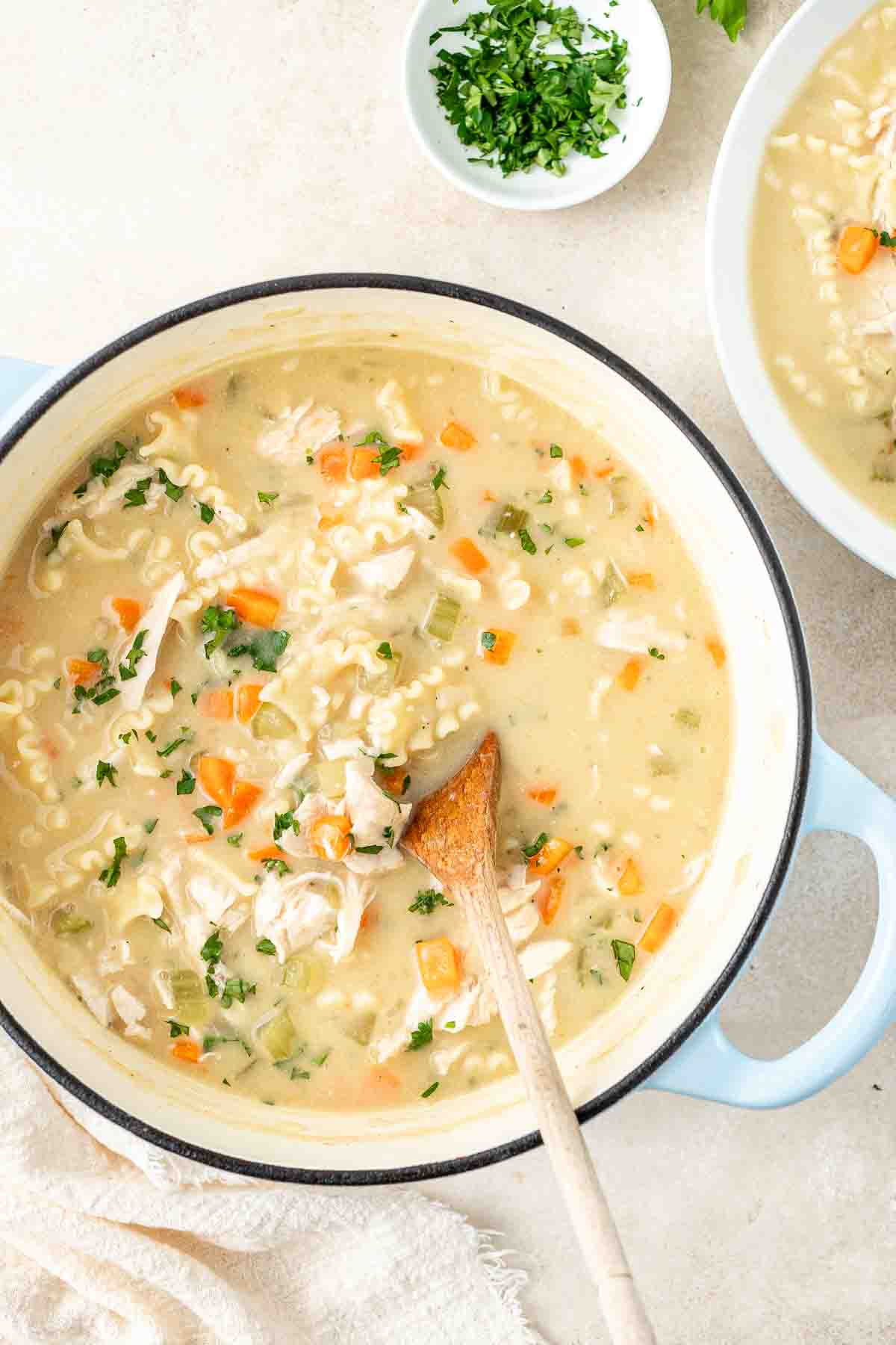 Dairy free creamy chicken soup in a large dutch oven with a wooden spoon.