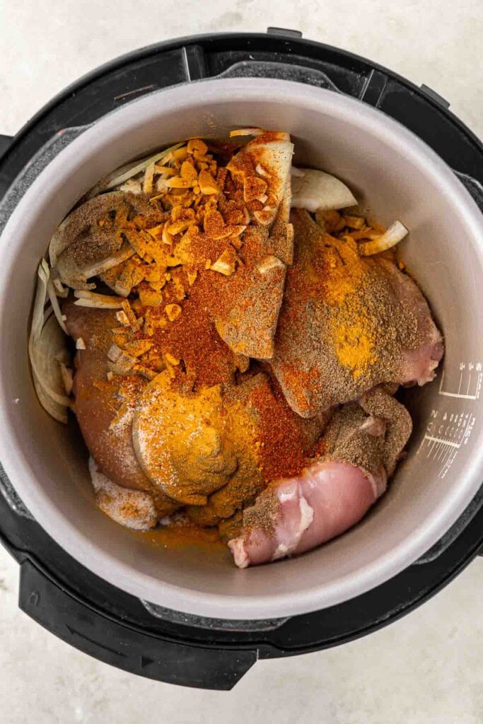 Adding the chicken and spices to the bowl of the slow cooker.