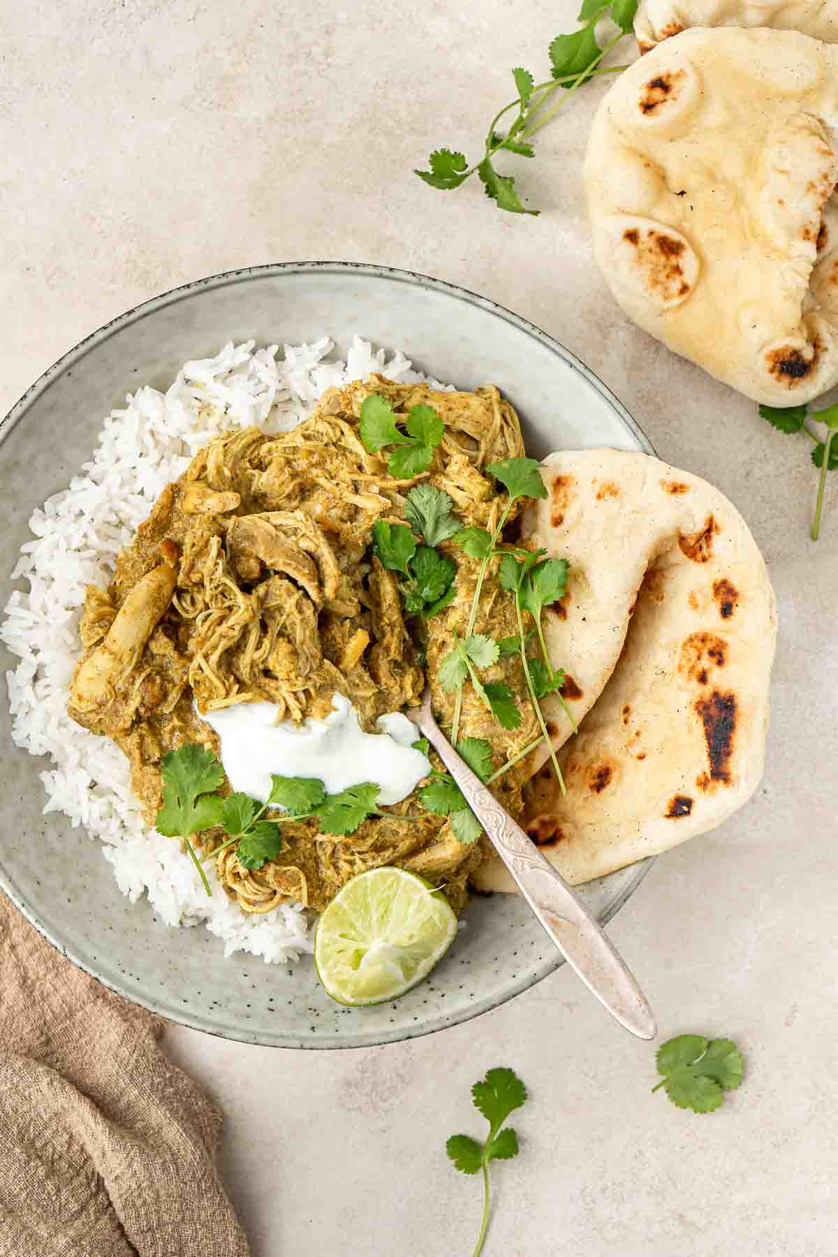 Slow cooked coconut chicken curry served in a bowl with white rice and naan bread.