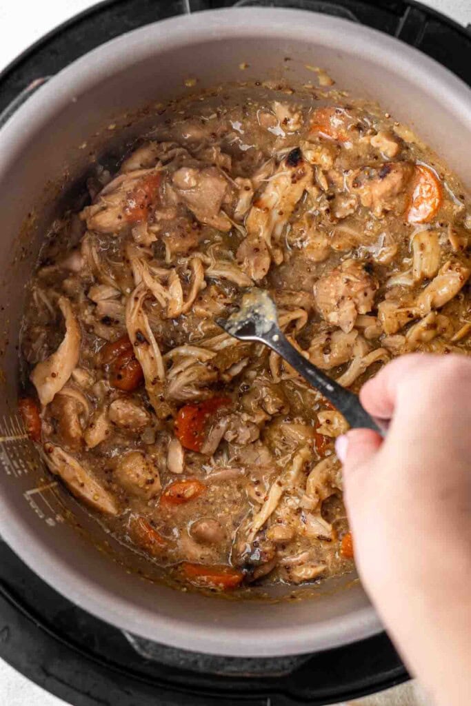 Shredding the chicken in the slow cooker with a fork.