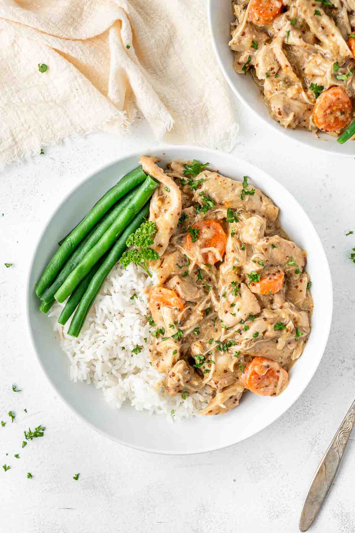 Slow cooked honey mustard chicken served in a white bowl with rice and beans.