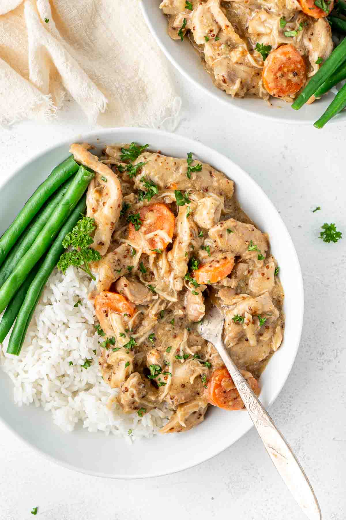 Slow cooked honey mustard chicken in a bowl with green nbeans and rice.