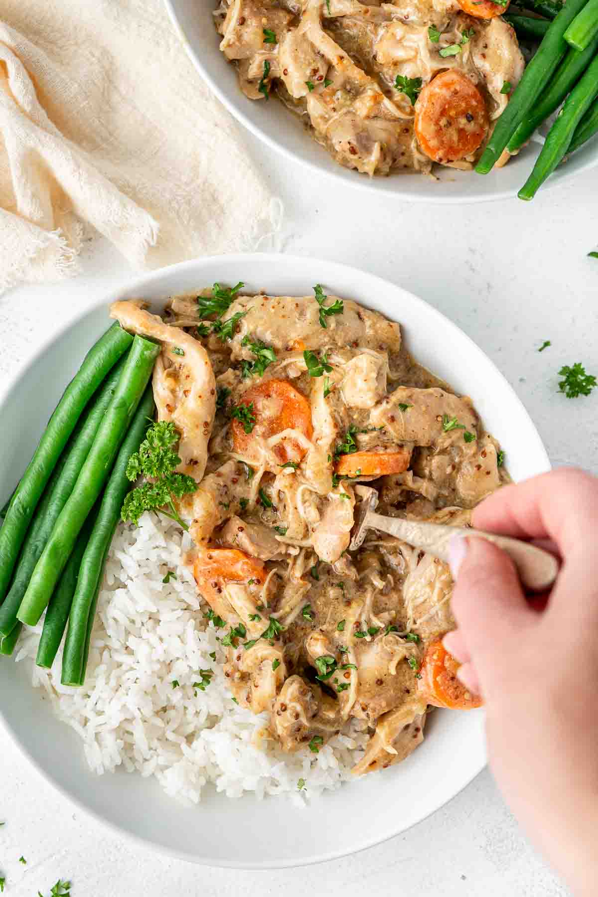 Overhead of honey mustard chicken with rice and green beans with a hand taking a forkful.