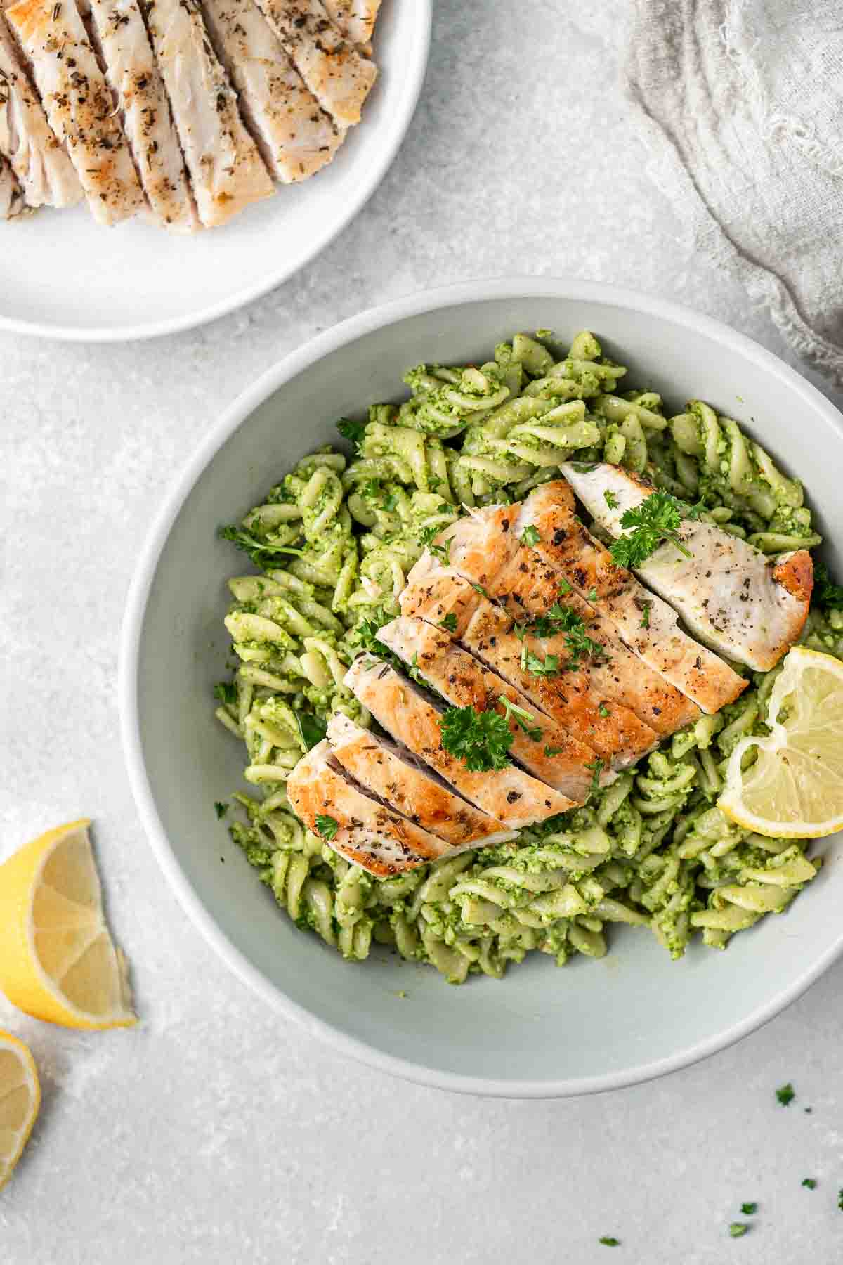 Grilled chicken sliced over spinach pesto pasta.