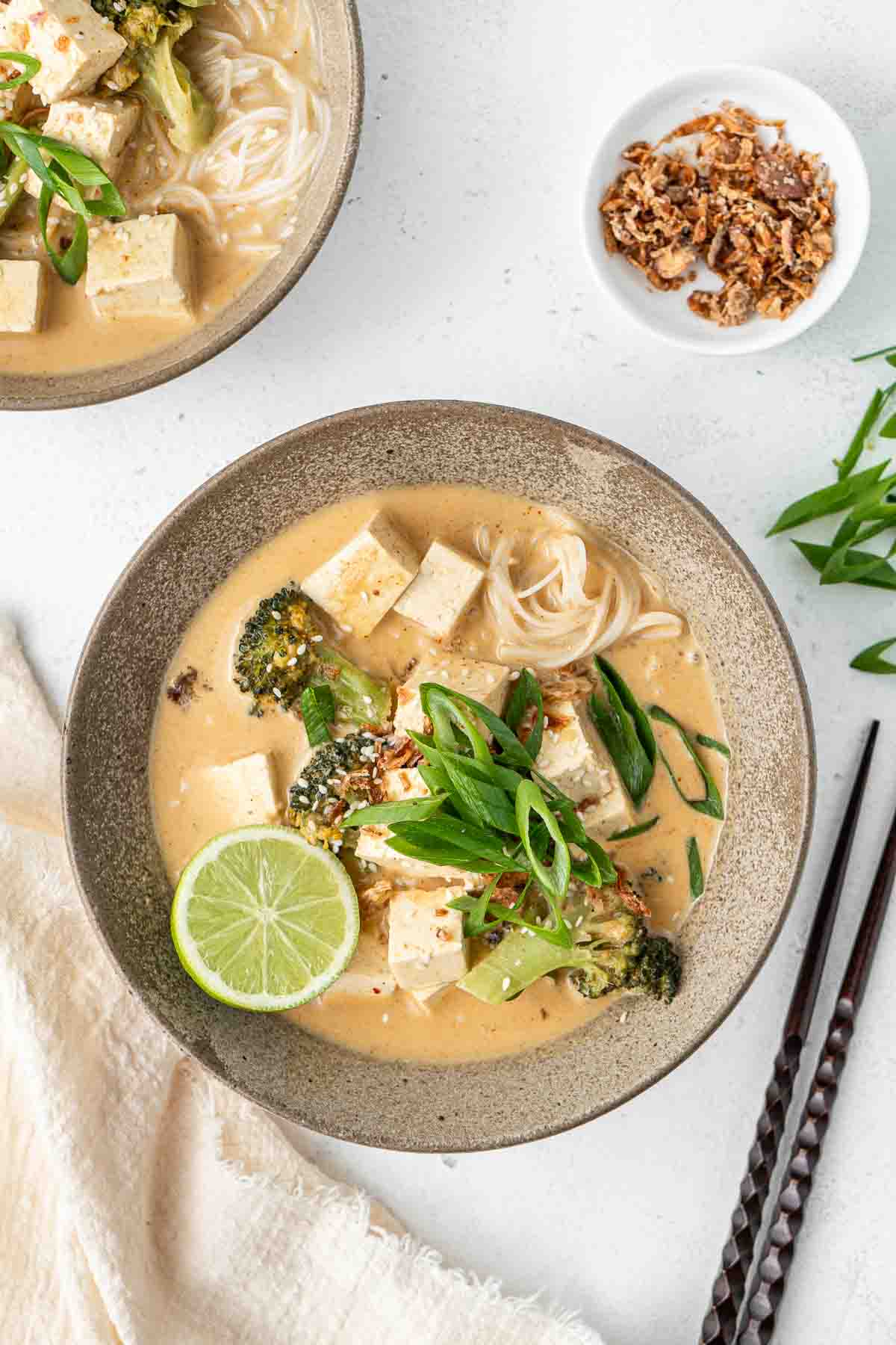 Thai red curry soup served in a bowl with fresh lime and spring onions.