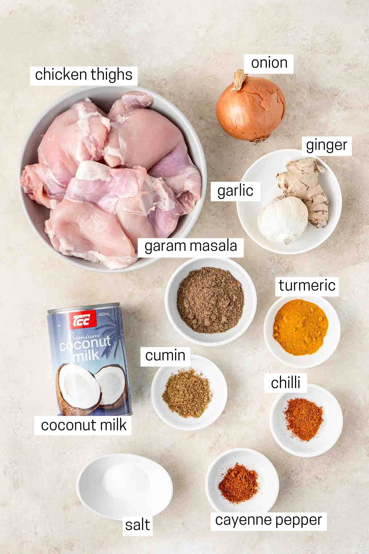 All ingredients needed to make slow cooekr coconut chicken curry laid out in small bowls.