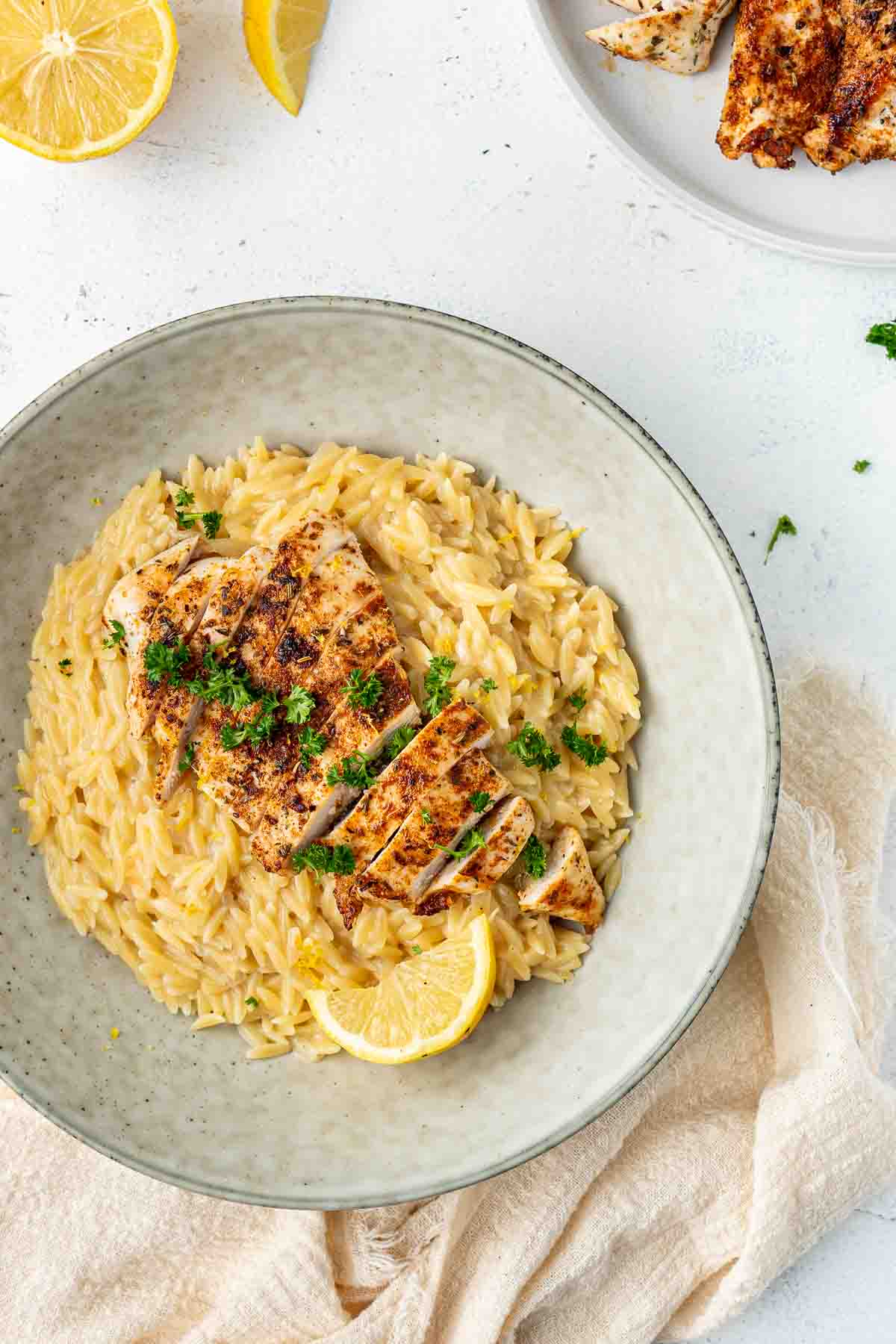 Dairy free creamy lemon risoni in a bowl with sliced grilled chicken.