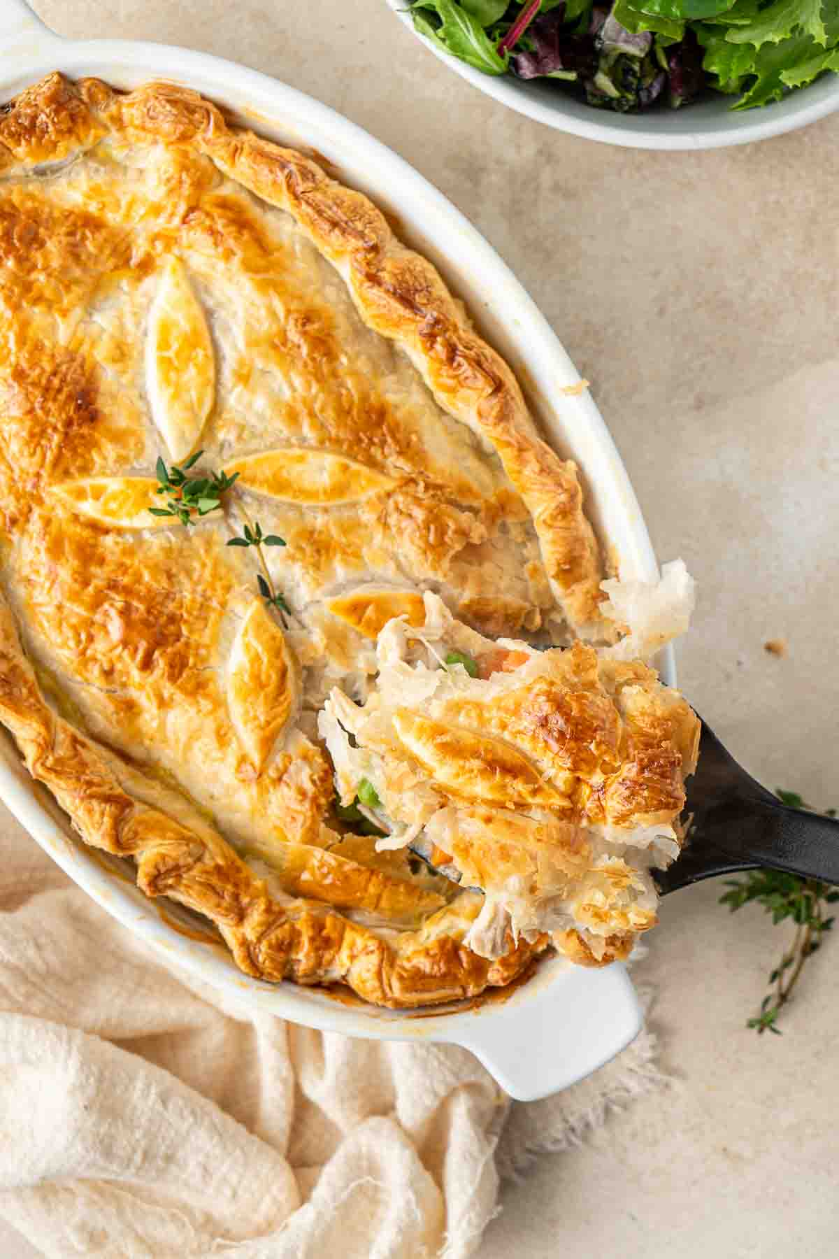 A spoon taking a serve of chicken pot pie from the dish.